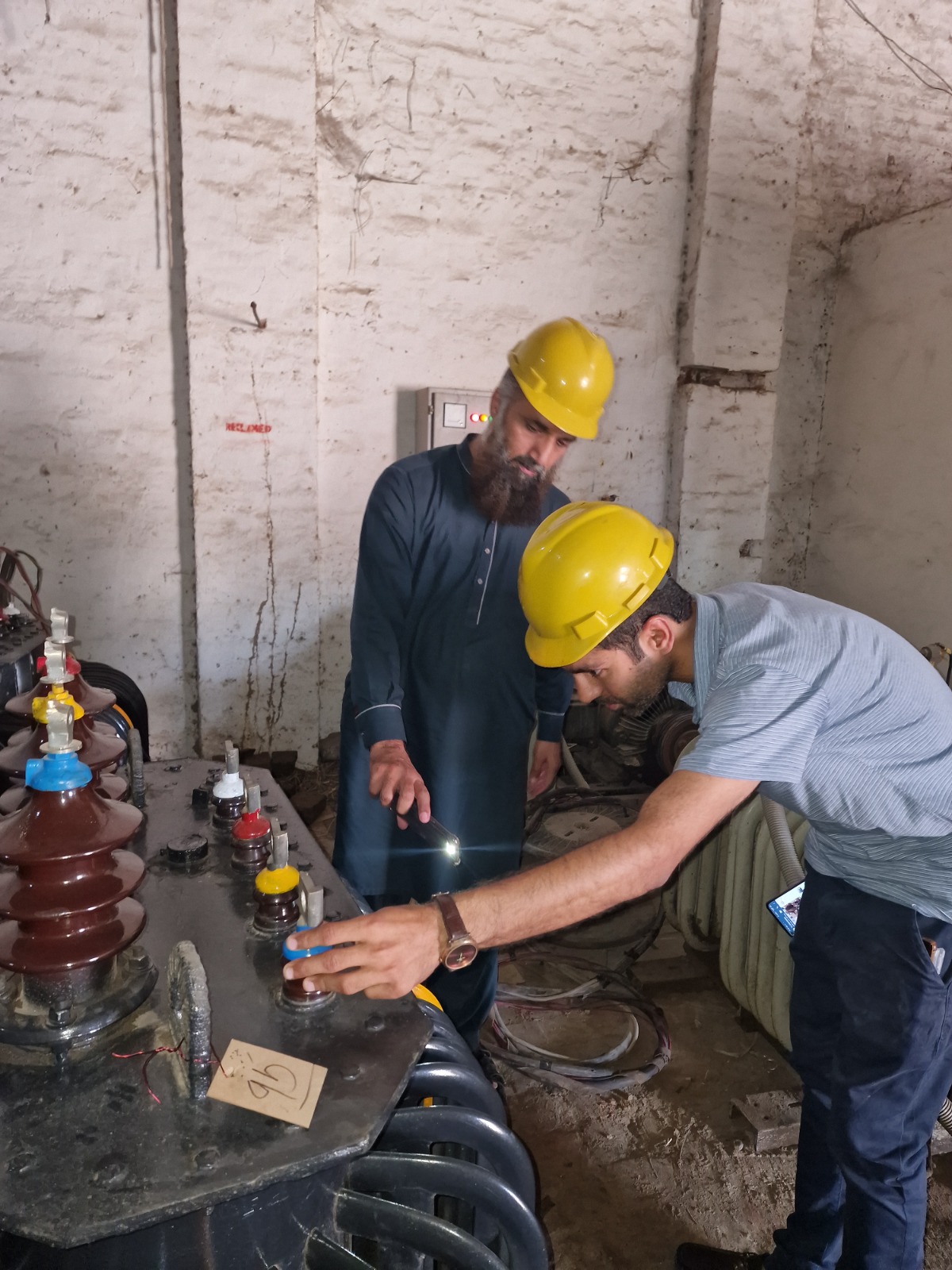 Ghazi Electric Works personnel inspecting a transformer — company photograph